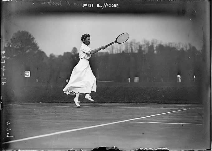 woman leaping after tennis ball in long skirt